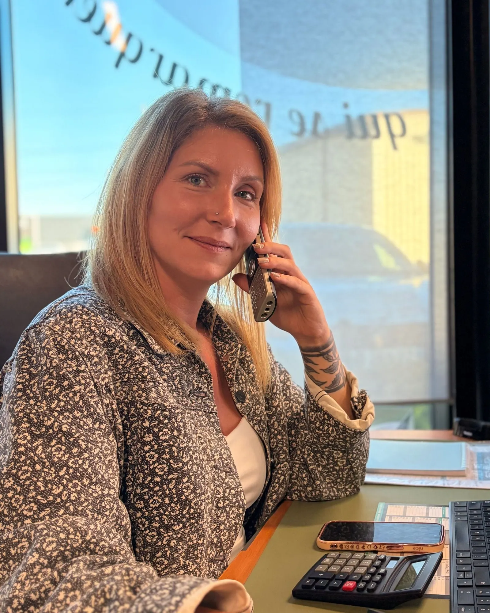 Marine au téléphone à son bureau, calculatrice et clavier devant elle