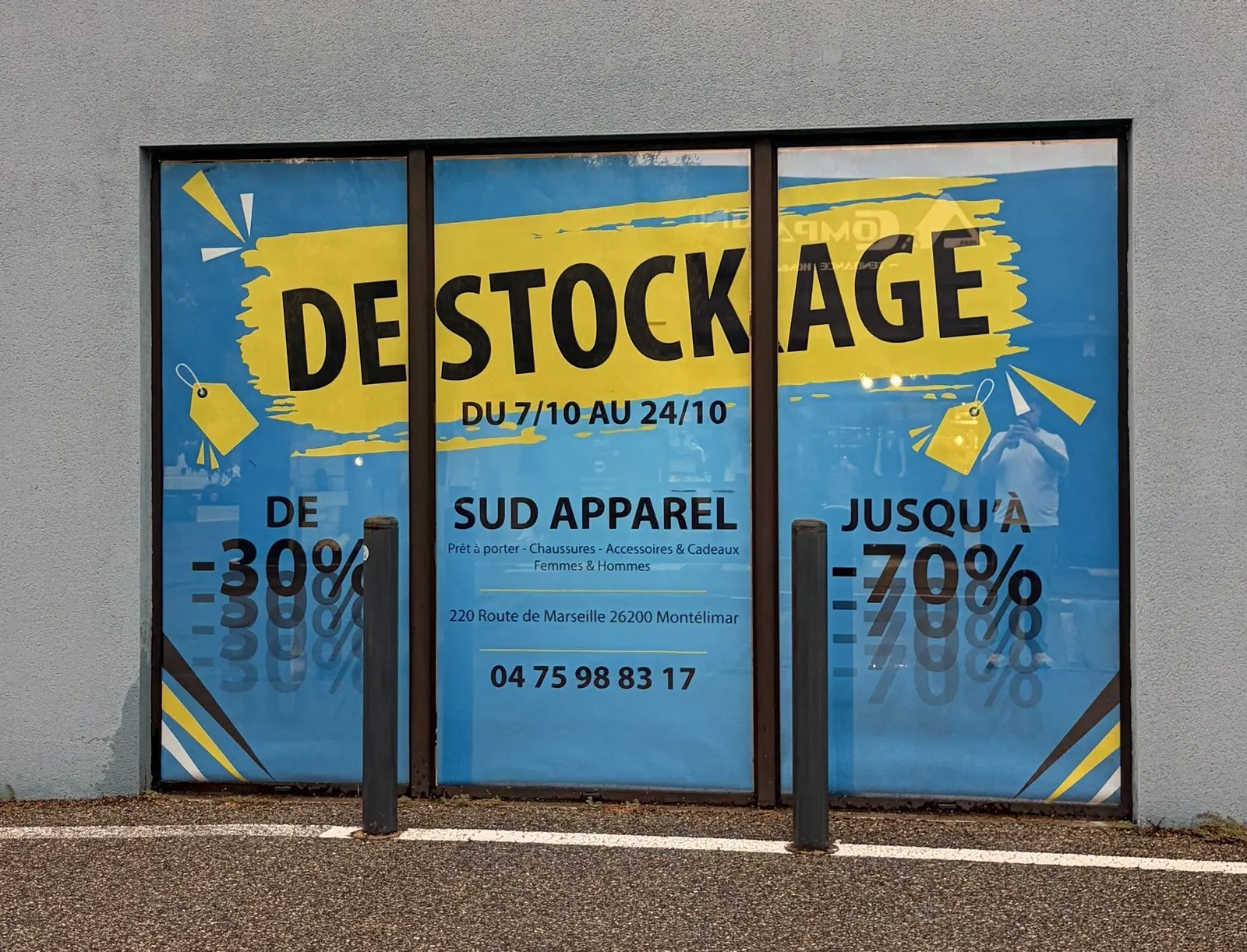 Grande affiche « déstockage » jaune et bleue collée en vitrine