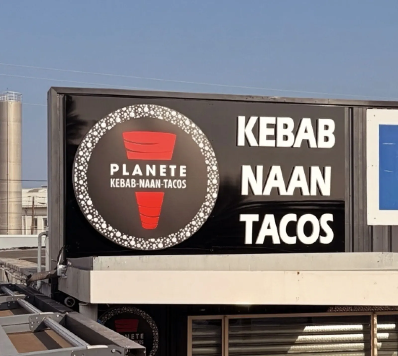 Enseigne noire de restaurant avec logo rond et lettres blanches
