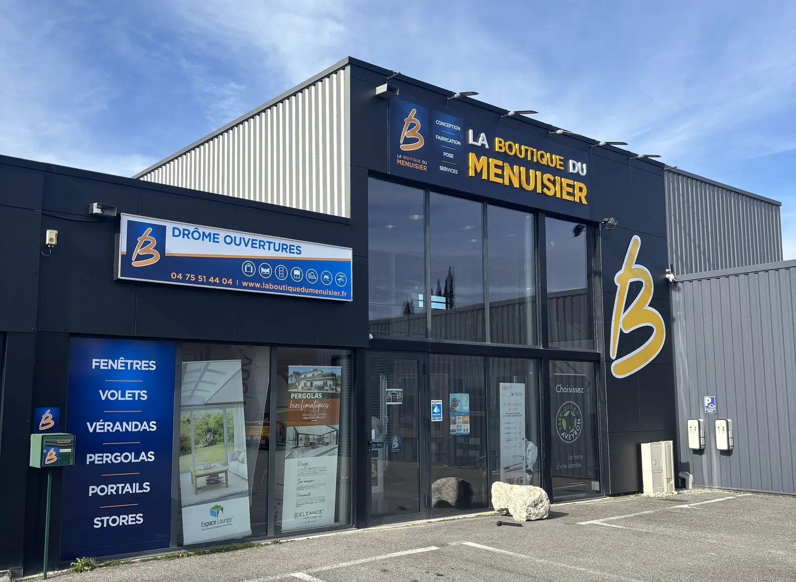 Façade de magasin avec enseigne en lettres jaunes, panneau et vitrines habillées