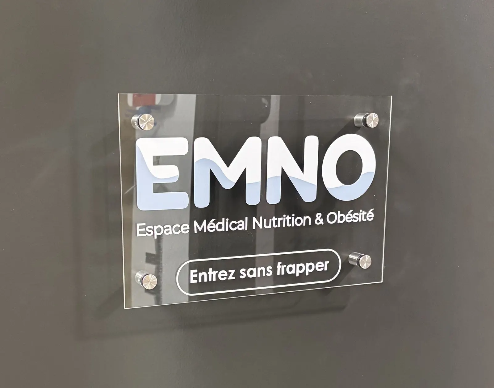 Plaque professionnelle transparente sur un mur sombre