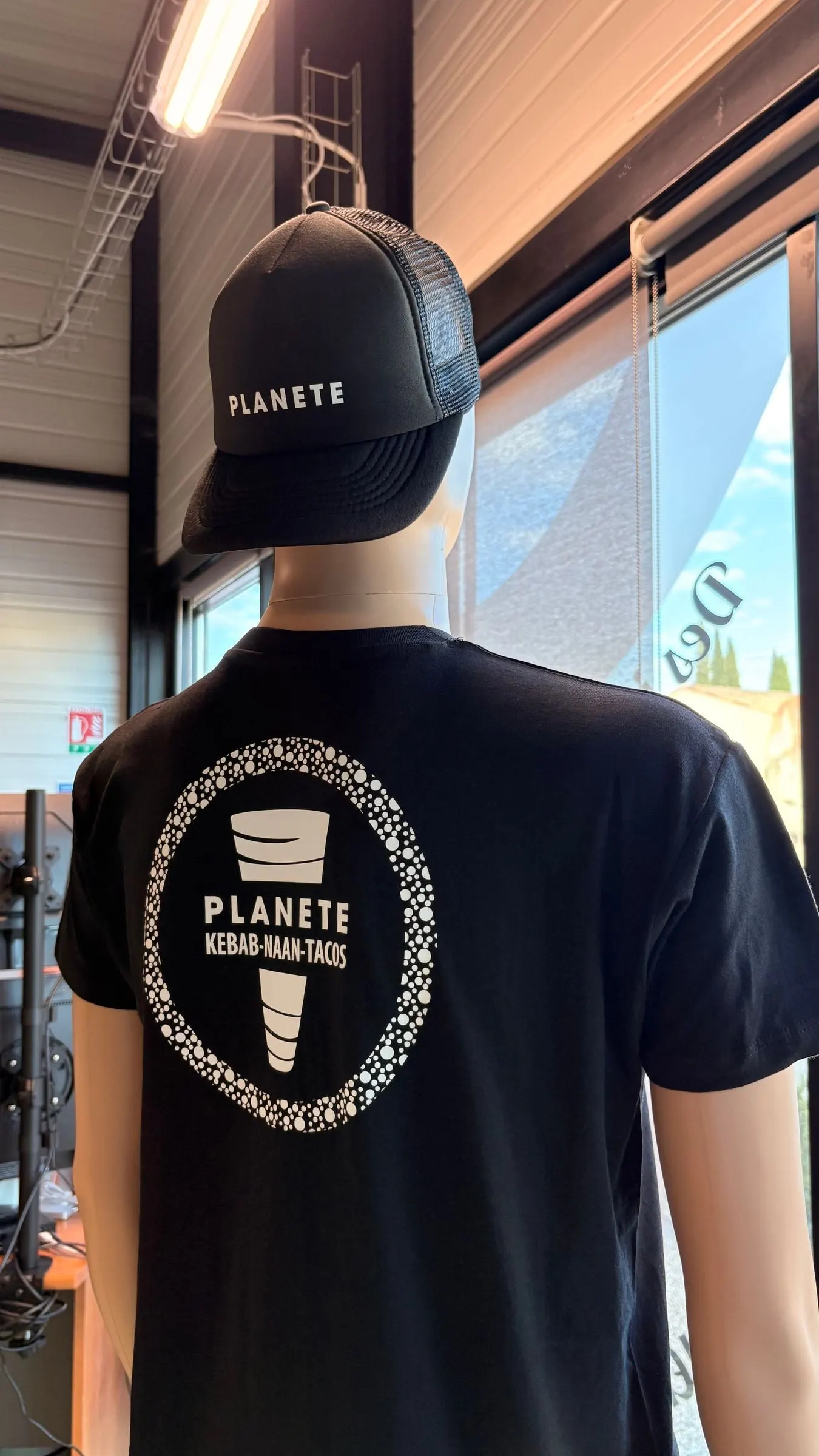 Mannequin portant un t-shirt noir marqué dans le dos et une casquette